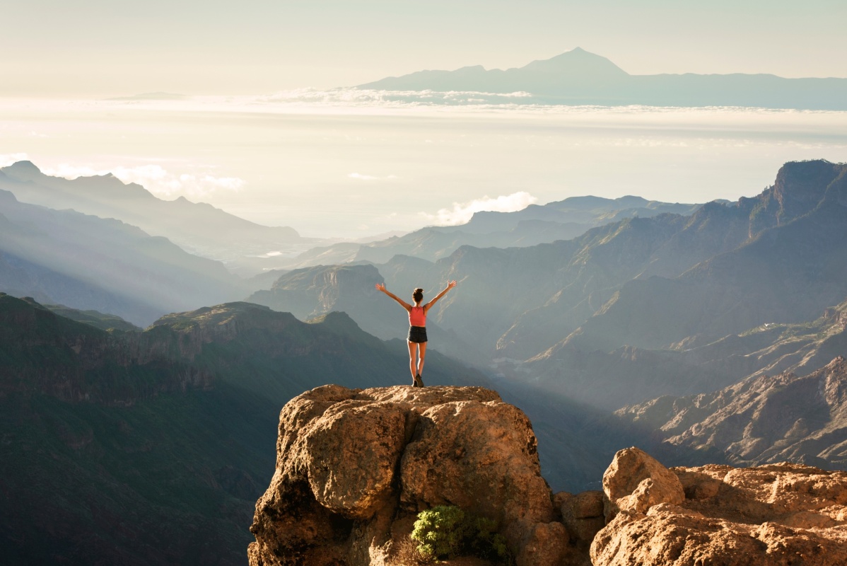 Vista panorámica desde Roque Nublo en Gran Canaria con una persona disfrutando del paisaje.
