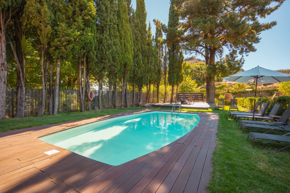 View of the garden at Hotel Rural El Refugio Gran Canaria, which includes a swimming pool and garden chairs.